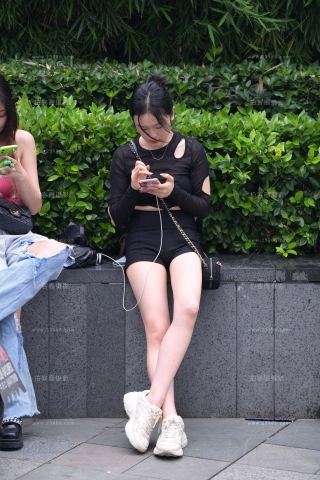 抓拍坐在花坛边的美腿女孩